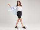 A woman is wearing the Mel biker in black with a white bodysuit and blue button-down shirt standing. Yummie