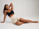 mona shaping short - seamless in Frappe and audrey unlined bralette - outlast® seamless in Black worn by a model sitting on ground leaning on one arm and the other on neck Yummie