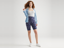 mel shaping biker short - cotton stretch in Eclipse Blue Camo, ruby shaping thong bodysuit - cotton seamless in Heather Grey and a denim shirt worn by a woman standing facing forward with legs apart and right hand  touching hair, left arm at side Yummie