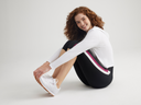  talia cropped capri shaping legging - cotton stretch in Black with Blackberry/White Stripe and cropped lounge hoodie - cotton rib in White worn by a woman stitting on the ground, knees bent and hands holding feet Yummie