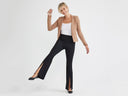 A woman is wearing the Chrissy Split Bootcut Shaping Legging - 360Sculpt™ Cotton in black with a white top and camel blazer while standing. Yummie