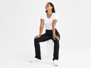 A woman is wearing the Jodi Legging in black and the Holly Short Sleeve Top in white while sitting. Yummie
