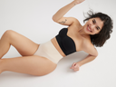 fran shaping thong – seamless in Nude worn by woman laying on the ground Yummie