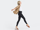 a woman is wearing the Rachel Shaping Legging - 360Sculpt™ Cotton in black with a white top and camel blazer while standing with arms extended. Yummie