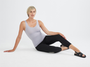 A woman is wearing the Lena Tank in Dapple Grey with the Gloria Legging in Black while reclining on the floor. Yummie