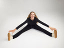 susie flare shaping legging - cotton stretch and cropped lounge hoodie - cotton rib in Black worn by a woman sitting on the ground with legs open and hands holding sneakers Yummie