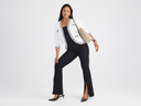 A woman is wearing the Chrissy Split Front legging in black with a black top and white sweater blazer. Yummie
