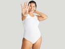 A woman is standing facing forward with right arm extended wearing  Ruby Shaping Full Back Bodysuit - Cotton Seamless in White Yummie